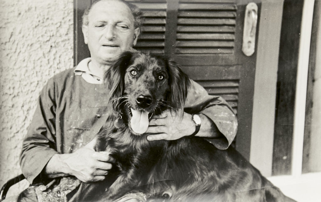 The artist Yohanan Simon sitting with a dog in the 1950s.